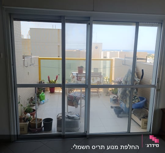 דלת חלון הזזה מאלומיניום עם רשתות נגד חרקים המוליכה למרפסת